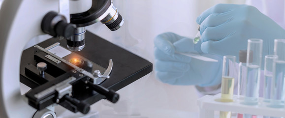Wall Mural - close-up shot of microscope with a blurred picture of research in the laboratory