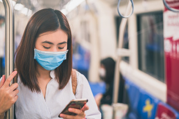 Young asian woman wearing protective face mask using smartphone in underground train due to the polluted air or pm 2.5 and Coronavirus or COVID-19 outbreak situation in all of landmass in the world.