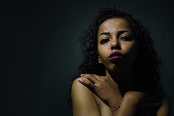 Wall Mural - young naked African woman posing at studio, face with hand portrait over dark background