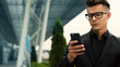 © VAKSMANV - Businessman in eyeglasses using cell phone in the city