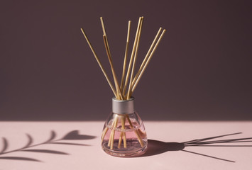 aromatic reed air freshener on pink background hard shadow. aromatherapy sticks. air refresher bottl