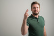 © Cipri Suciu  - Portrait of serious stylish attractive man with thick beard, dressed in casual green t shirt showing fingers crossed