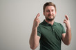 © Cipri Suciu  - Portrait of serious stylish attractive man with thick beard, dressed in casual green t shirt showing double fingers crossed