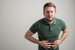 © Cipri Suciu  - Portrait of serious stylish attractive man with thick beard, dressed in casual green t shirt gesturing stomach ache
