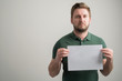 © Cipri Suciu  - Portrait of serious stylish attractive man with thick beard, dressed in casual green t shirt holding white paper