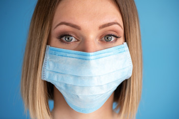 Nurse or doctor with face mask. Close up portrait of young caucasian woman model on blue background