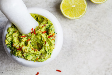 Poster - Cooking guacamole - avocado sauce in a white stone mortar, top view.