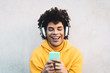 © Alessandro Biascioli - Happy Afro man using mobile smartphone outdoor - Young guy having fun listening music with wireless headphones outdoor - Youth millennial generation lifestyle and people addicted technology concept