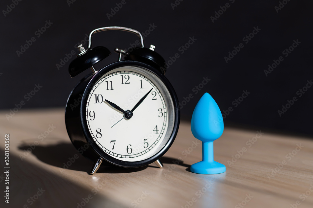 Blue latex anal plug and alarm clock on a wooden table. The time of carnal  pleasures. Stock Photo | Adobe Stock