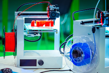 Poster - 3D printers close up. Print objects from blue and red materials. Method of layer-by-layer model construction. The printer prints a three-dimensional object. Modern technology.