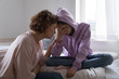 © fizkes - Worried parent young mom comforting depressed crying teen daughter bonding at home. Loving understanding mother apologizing or supporting sad teenage girl having psychological puberty problem concept.