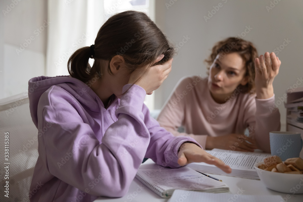 Angry adult mother scolding lazy teen daughter for bad school results at home. Frustrated mum talking to upset teenage girl arguing disciplining child must study. Parent and children conflicts concept - obrazy, fototapety, plakaty 