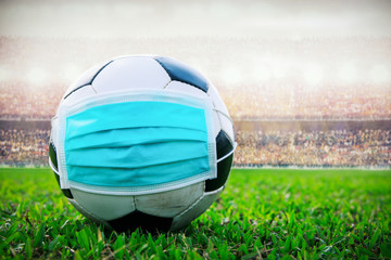 soccer ball with medical mask in the stadium. All event of soccer pause break. covid-19 spreading outbreak