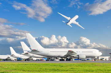 Wall Mural - View of the standing planes at the airport and airplane taking off in the sky.