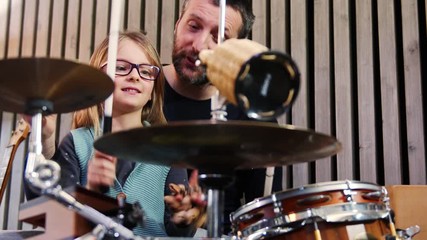 Wall Mural - Father and daughter play percussion together.Little girl learning drums with her dad at home.Front view.Percussion class at home