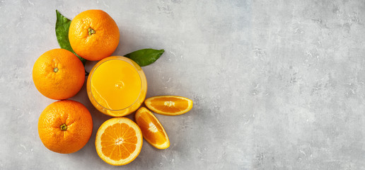 Wall Mural - Top view of fresh orange juice, oranges and slices on grey concrete background