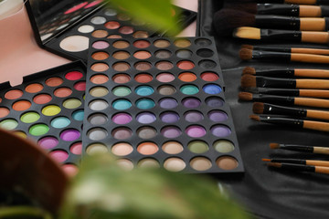 A palette of shadows and brushes on the table next to the flowers