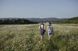 © Olena_Molchanova - two cute teen girls in denim overalls walk in a daisy field