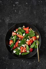 Wall Mural - Strawberry and spinach spring salad in a black plate