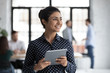 Smiling young Indian female employee hold tablet look in distance thinking, happy millennial biracial woman worker distracted from pad gadget, lost in thoughts visualizing, business vision concept