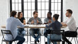 © fizkes - Diverse multiracial businesspeople sit at desk in office brainstorm discuss business ideas together, concentrated multiethnic colleagues gather in boardroom negotiate at meeting or briefing