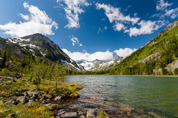 Wall Mural - Green lake between mountains in cloudy day