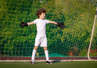 Wall Mural - Summer soccer tournament for young kids. football club. emotions and joy of the game. Young goalie. Kids - soccer champion. Boy goalkeeper in football sportswear on stadium with ball. Sport concept.