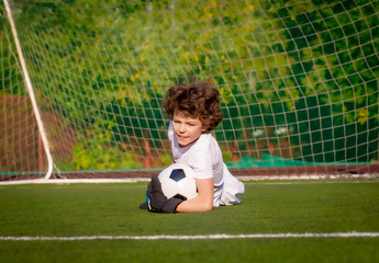 Wall Mural - Summer soccer tournament for young kids. football club. emotions and joy of the game. Young goalie. Kids - soccer champion. Boy goalkeeper in football sportswear on stadium with ball. Sport concept.