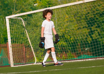 Wall Mural - Summer soccer tournament for young kids. football club. emotions and joy of the game. Young goalie. Kids - soccer champion. Boy goalkeeper in football sportswear on stadium with ball. Sport concept.