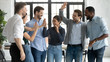 © fizkes - Overjoyed multiracial colleagues have fun celebrate shared business victory or win at workplace, happy diverse multiethnic businesspeople engaged in funny teambuilding activity in office together