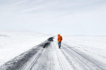 Wall Mural - man in red hooded jacket walking on snow covered road