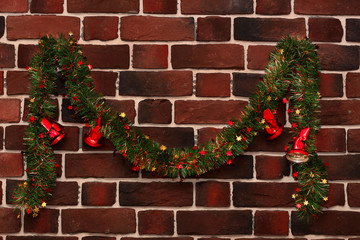 Wall Mural - green garland with red christmas bells on a brick wall