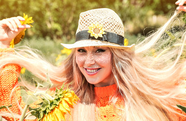 Wall Mural - Caucasian beautiful woman in hat posing  with sunflowers.