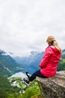 Female tourist sitting on the cliff edge near Flydalsjuvet Viewpoint. Travel Norway,