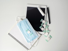 Tablet, Notepad, Pen And Protective Equipment: Alcohol Gel, Napkins, Masks On A White Table. The Concept Of Protecting And Disinfecting The Workspace From Viruses And Bacteria.