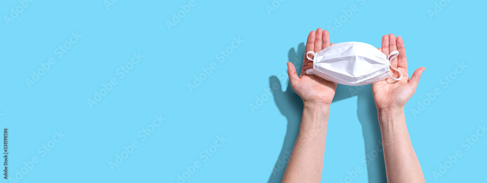 Person holding a white surgical mask overhead view - flat lay - obrazy, fototapety, plakaty 