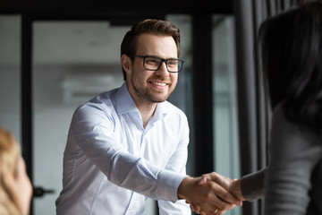 Wall Mural - Smiling middle-aged male employee shake hand close deal make agreement with female coworker at meeting, happy businesspeople handshake get acquainted or greeting with success at briefing