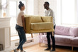 © fizkes - Young happy african american couple moving and carry table. Attractive family of diverse woman and man relocation furniture in new home. Husband and wife perform permutation.