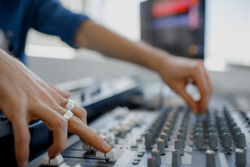 Hand on a mixer, operating the leader. Sound engineer working at mixing panel in the recording studio. Hands adjusting audio mixer. Close up concept.