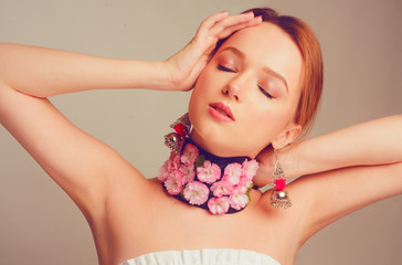 Wall Mural - Gorgeous girl, spring, with flowers on her neck. Bandage of fresh pink flowers, checker. Gorgeous beauty brunette, portrait. A girl with ceres and beautiful delicate make-up in the studio.