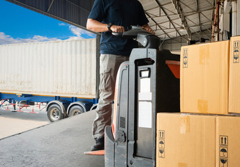 Wall Mural - Warehouse worker driving forklift pallet jack unloading pallet goods, package boxes, road freight transport, warehouse industry delivery logistics and transport.