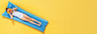Top view on a little girl in a swimsuit and half glasses of orange resting on an inflatable blue mattress on a yellow background, concept of summer vacation. Banner copy space