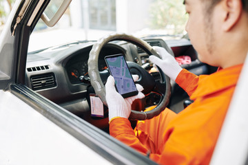 Wall Mural - Delivery service worker checking map via mobile application before driving to destination point