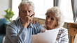 © fizkes - Unhappy older couple reading documents, checking domestic bills, caring mature wife comforting sad upset husband holding debt notification, stressed about financial problem or bankruptcy