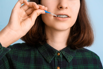 Wall Mural - Teenage girl with dental braces and brush on light background, closeup