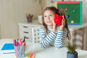 Education, school and money saving concept - child holds a red piggy Bank