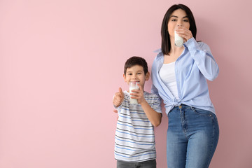 Canvas Print - Mother with her little son drinking milk on color background