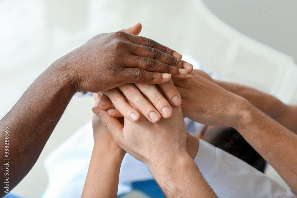 Group of people putting hands together indoors. Unity concept