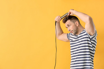 Wall Mural - Handsome young man with flattening iron on color background