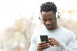 © PheelingsMedia - Happy black man listening music on phone with headphones